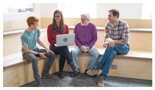 Image of four people looking at a laptop